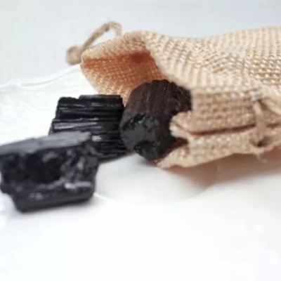 Pedaços de carvão preto e saco de tecido bege.