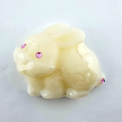 Escultura de coelho amarelo claro com olhos e cauda rosa