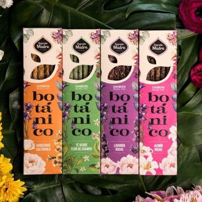 Quatro embalagens de sabonetes botânicos Sagrado Madre em verde, laranja, lavanda e rosa com flores ao redor