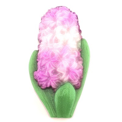 Vela decorativa em forma de flor com pétalas rosa, branco e folhas verdes.