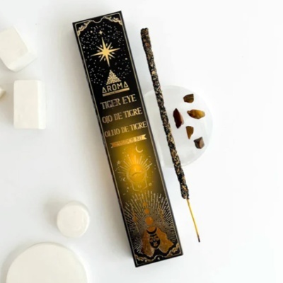 Caixa e bastÃ£o de incenso AromÃ Tiger Eye em fundo branco com pedrinhas castanhas e objectos brancos