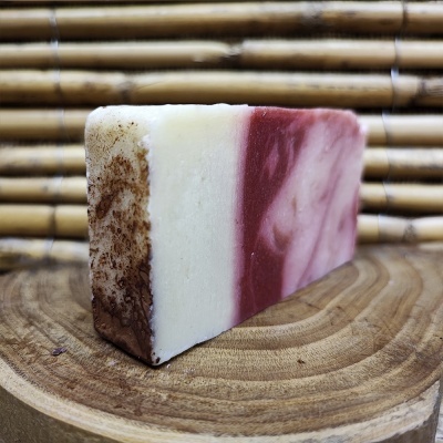 Barra de sabão artesanal tricolor sobre base de madeira com fundo de bambu