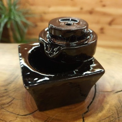 Fonte decorativa em cerâmica preta sobre superfície de madeira