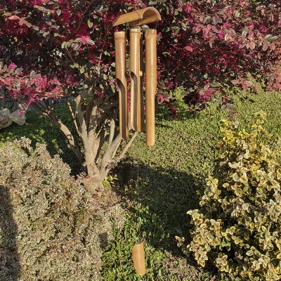 Sino dos ventos de madeira pendurado em árvore com folhagem colorida