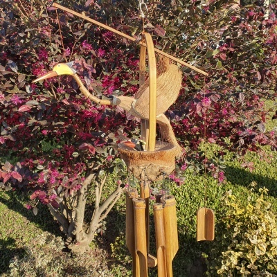 Móbile de pássaro em madeira e fibras naturais pendurado em jardim colorido