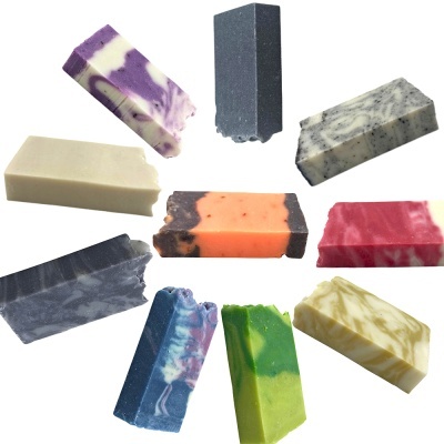 Dez barras coloridas e variadas de sabão artesanal sobre fundo branco