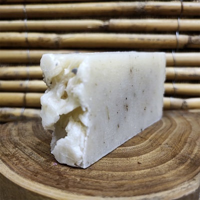 Barra de sabão branca com textura irregular sobre prato de madeira