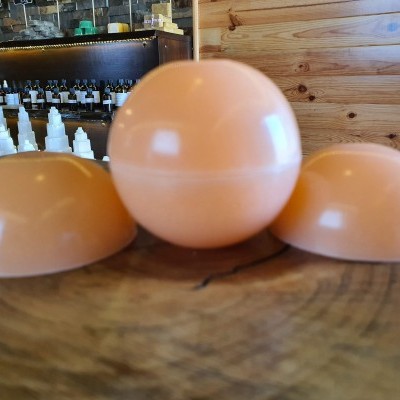 Três bolas bege claro brilhantes sobre madeira com garrafas desfocadas ao fundo