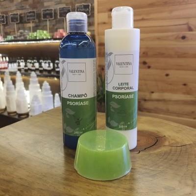 Produtos VALENTINA COSMÉTICOS para psoríase: champô, leite corporal e sabonete sobre mesa de madeira