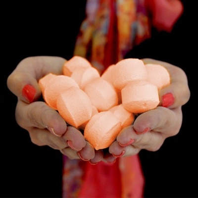 Mãos segurando pastilhas laranja