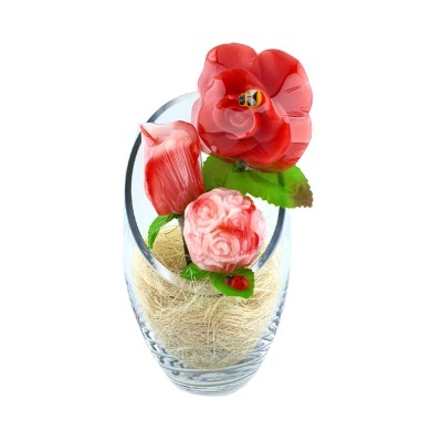 Vaso de vidro com flores decorativas vermelhas e rosa com folhas verdes e inseto amarelo preto.