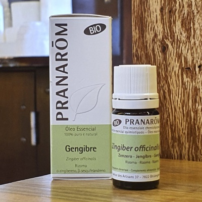 Embalagem e frasco de óleo essencial Pranarôm Bio Gengibre com design branco e verde claro sobre superfície de madeira