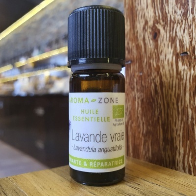 Pequeno frasco de óleo essencial de lavanda com rótulo em português e verde sobre mesa de madeira