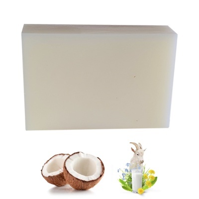 Bloco branco liso com coco cortado e cabra com garrafa de leite e flores.