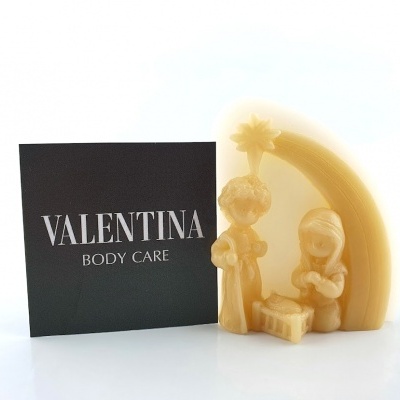 Escultura amarela do presépio ao lado de cartão preto com texto VALENTINA BODY CARE