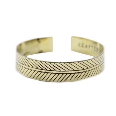 Pulseira aberta dourada com padrão de linhas diagonais