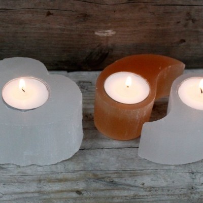 Três castiçais em forma de coração com velas acesas em cristal translúcido branco e âmbar