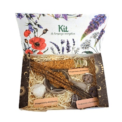 Kit de limpeza energética em caixa decorada com flores, com paus aromáticos e cristais, etiquetas indicam 'Prosperidade y abundancia' e 'Purificação e abundância'.