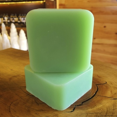 Dois sabonetes verdes em cubo sobre tábua de madeira