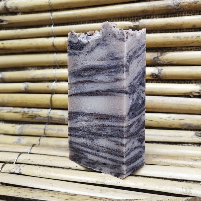 Barra de sabão artesanal cinza e branca sobre varas de bambu