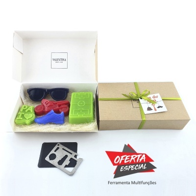 Caixa aberta com sabonetes coloridos e caixa de presente com fita verde junto a ferramenta multifunções preta