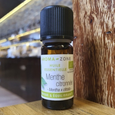 Frasco pequeno de óleo essencial de mentha x citrata da marca AROMA-ZONE sobre madeira