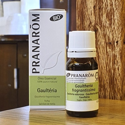 Frasco e embalagem de óleo essencial Pranarôm Gaultheria sobre mesa de madeira