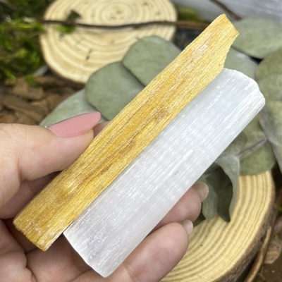 Dois pilares, um amarelo de madeira e outro branco translúcido, segurados por mão, com fundo natural