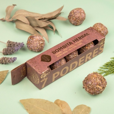 Caixa de bolas herbais com folhas secas ao redor sobre fundo verde