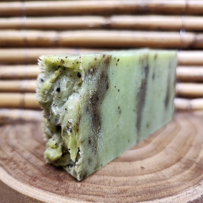 Sabonete artesanal verde com granulado preto sobre base de madeira