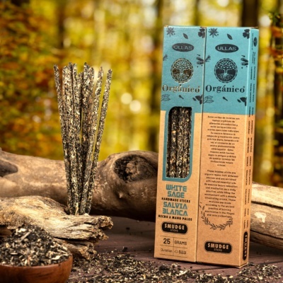 Caixas de incenso White Sage com gravuras e texto posadas sobre madeira rústica em floresta desfocada