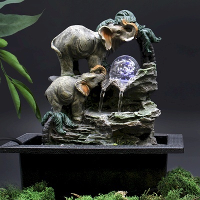 Fonte decorativa com elefantes e esfera luminosa sobre base preta