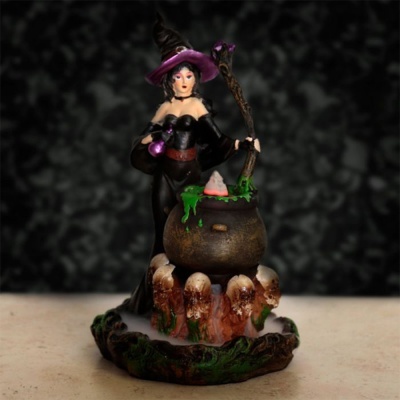Figura decorativa de feiticeira com caldeirão e detalhes em verde numa base com ossos.