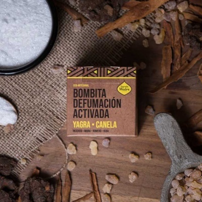 Caixa de bombita de defumação rodeada por especiarias sobre madeira e tecido