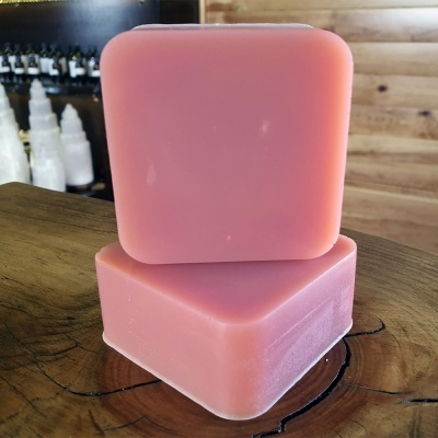 Dois blocos de sabão rosa empilhados sobre superfície de madeira com fundo desfocado