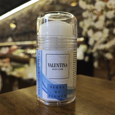 Desodorizante em bastão VALENTINA BODY CARE PEDRA DE ALÚMEN em embalagem transparente sobre mesa de madeira