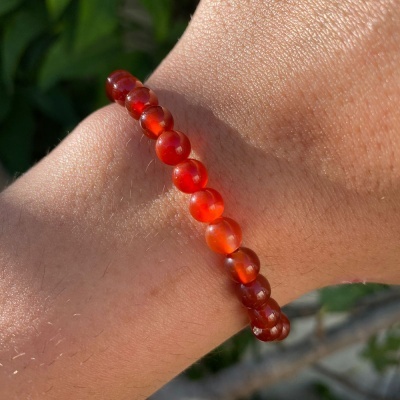 Pulseira de contas laranja translúcidas num pulso