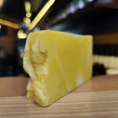 Bloco de queijo amarelo sobre superfície de madeira com fundo desfocado interior