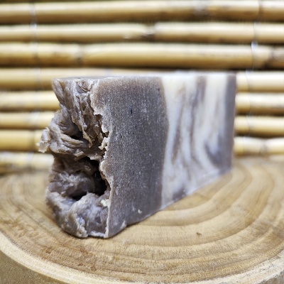 sabonete artesanal castanho creme textura rugosa sobre suporte de madeira