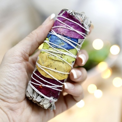 Maço de ervas colorido com pétalas, visto de perto, com luzes desfocadas ao fundo