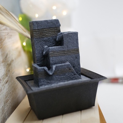 Fonte decorativa em pedra preta de três níveis com linhas douradas numa base preta