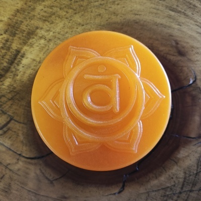 Velas redondas laranja com símbolo de flor em relevo sobre madeira