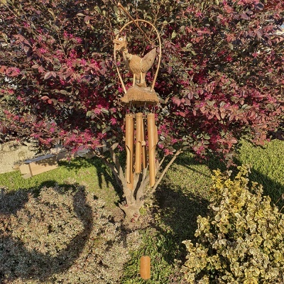 Móbile de vento de madeira e bambu pendurado em árvore com folhas roxas