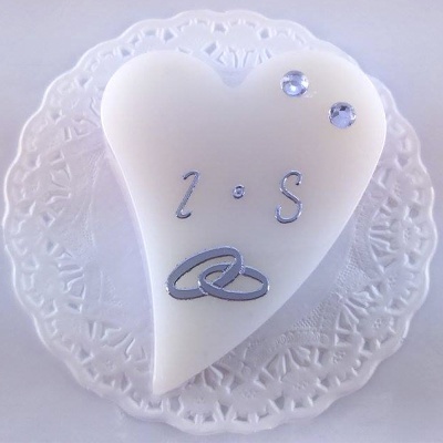 Bolo coração branco com decoração prateada e cristais sobre prato branco rendado