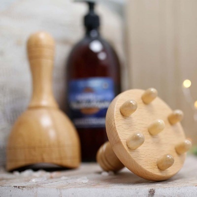 Dispositivos de massagem em madeira e frasco castanho em superfície clara