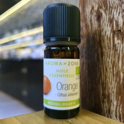 Frasco pequeno de óleo essencial de laranja com rótulo branco e verde