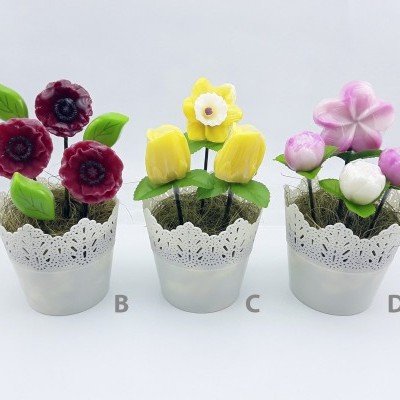 Três vasos metálicos com flores artificiais de feltro em vermelho, amarelo e rosa em fundo branco