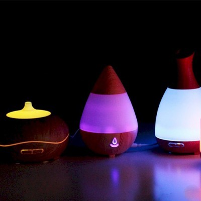 Três difusores de aroma em madeira com luzes coloridas