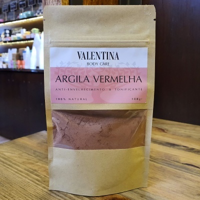 Pacote de argila vermelha em pó VALENTINA Body Care sobre mesa de madeira
