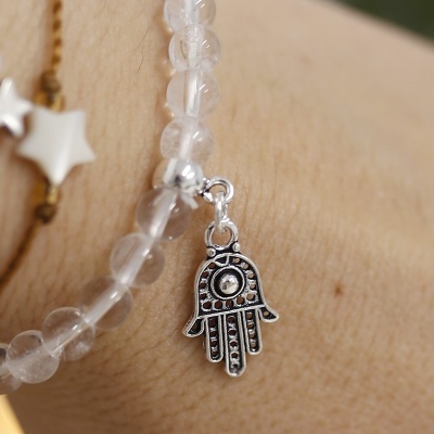 Pulseira transparente com pendente mão de Hamsá prateado no pulso